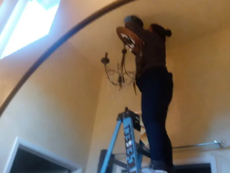 Electrician installing a chandelier in a Butler residence